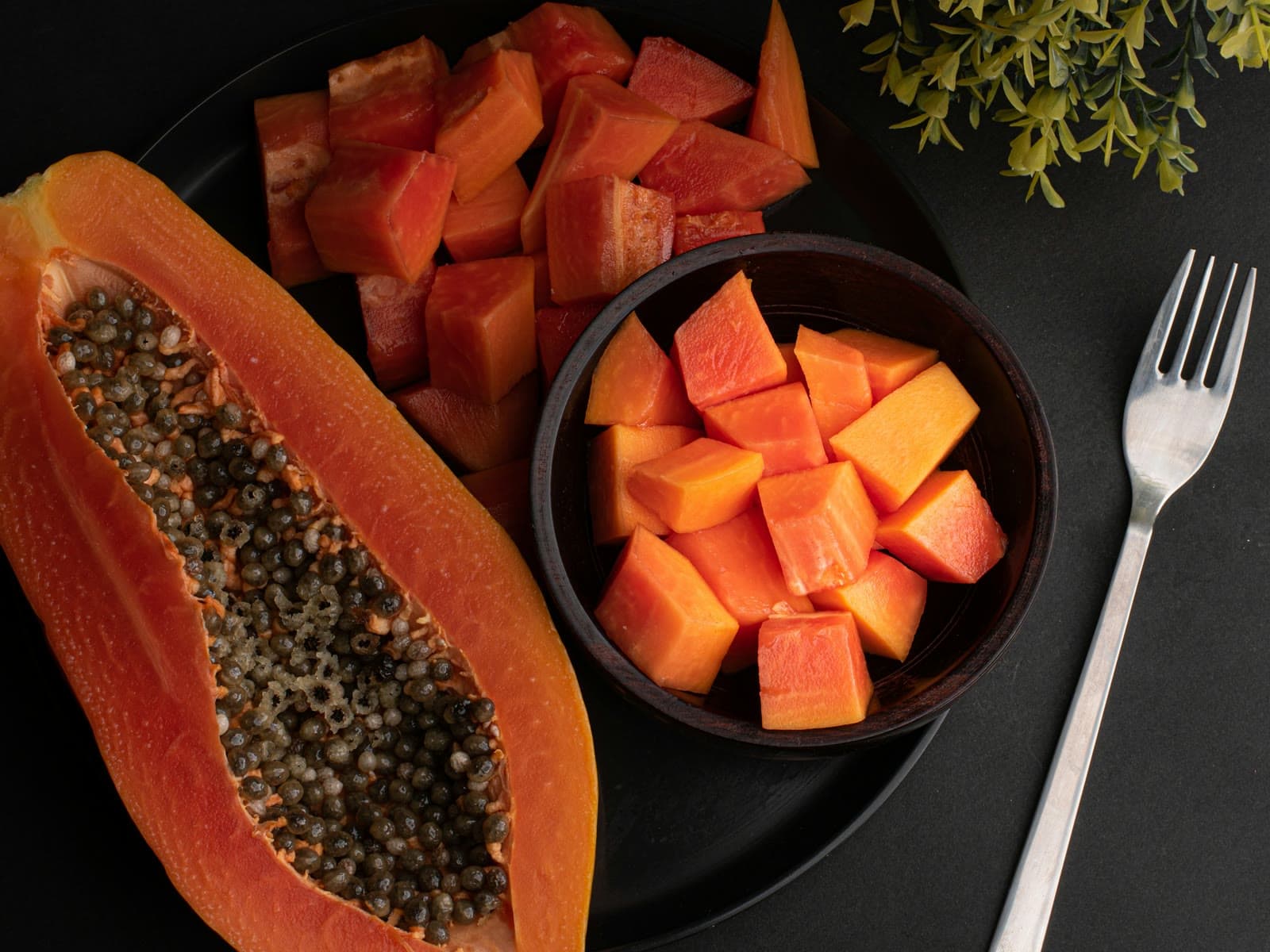 A halved pawpaw beside a bowl of diced pawpaw